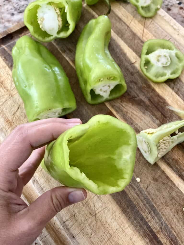 Showing the inside of a prepped Cubanelle pepper. Seeds and disgarded parts on a wooden cutting board below.