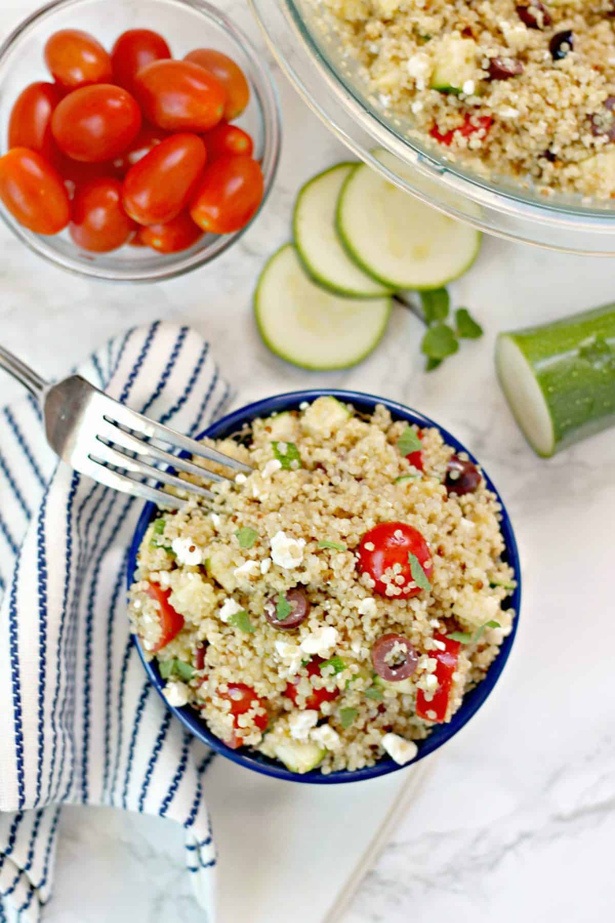 Overhead shot of Mediterranean Quinoa Salad with fork, sliced zucchini and grape tomatoes in bowl.