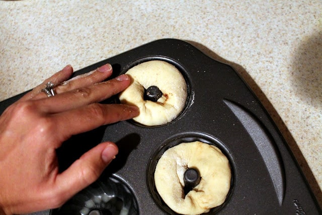 King cake dough being pressed into mini bundt cake pan for mini king cakes.
