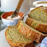 Close up shot of sliced Zucchini Bread with butter in a small bowl in background.