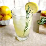 Vanilla Rosemary Lemonade in a glass garnished with a sprig of rosemary & a lemon wheel.