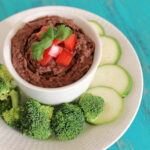 Cuban Black Bean Dip in a white serving dish surrounded by crudites.
