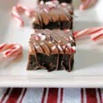 Peppermint Fudge Brownies on a white platter with candy canes.