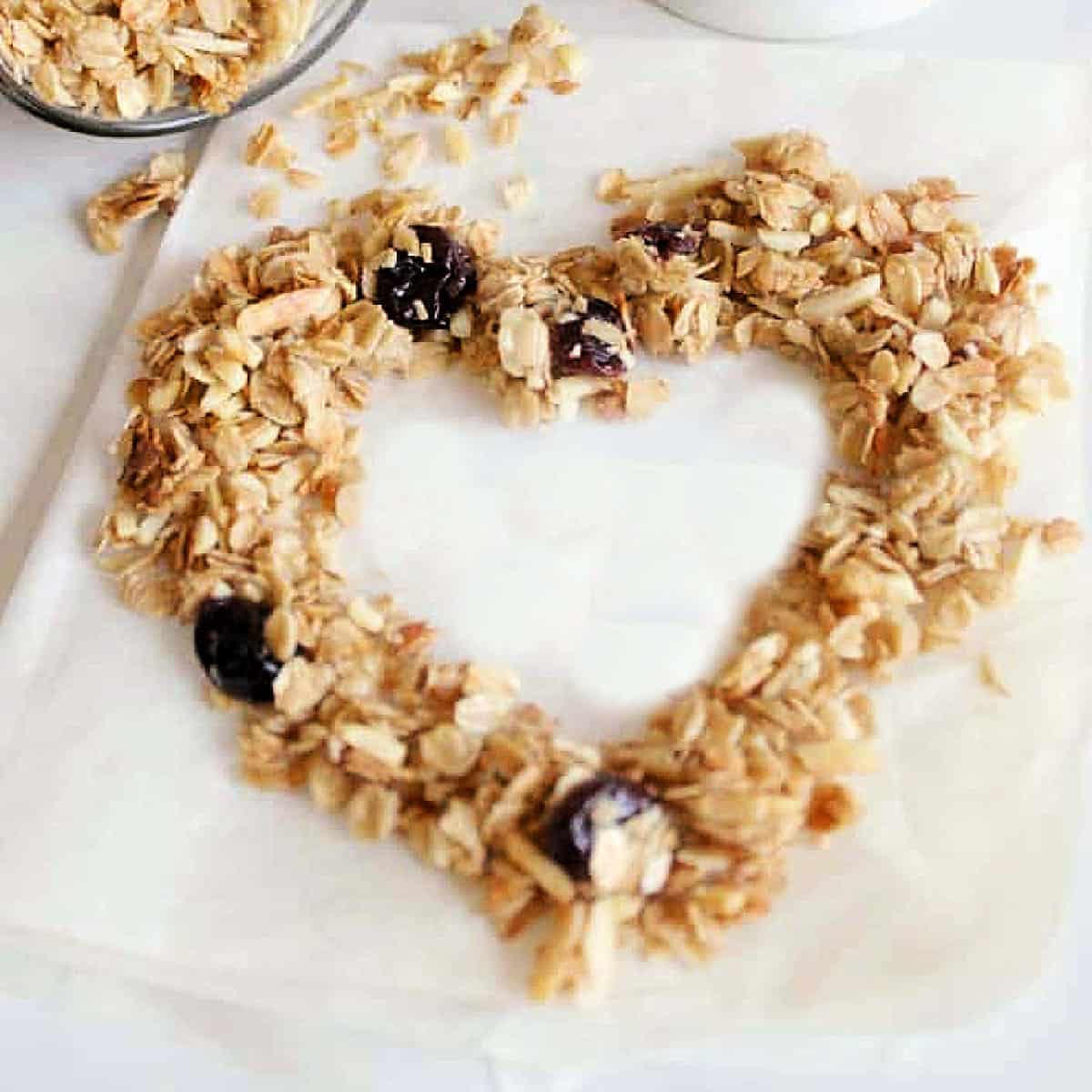 Cherry Vanilla Granola scattered on a piece of parchment paper in the shape of a heart.