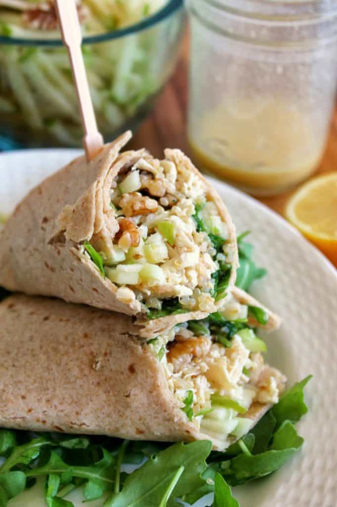 Healthy Chicken Wrap on a bed of arugula on a white plate, cut in half to show filling.