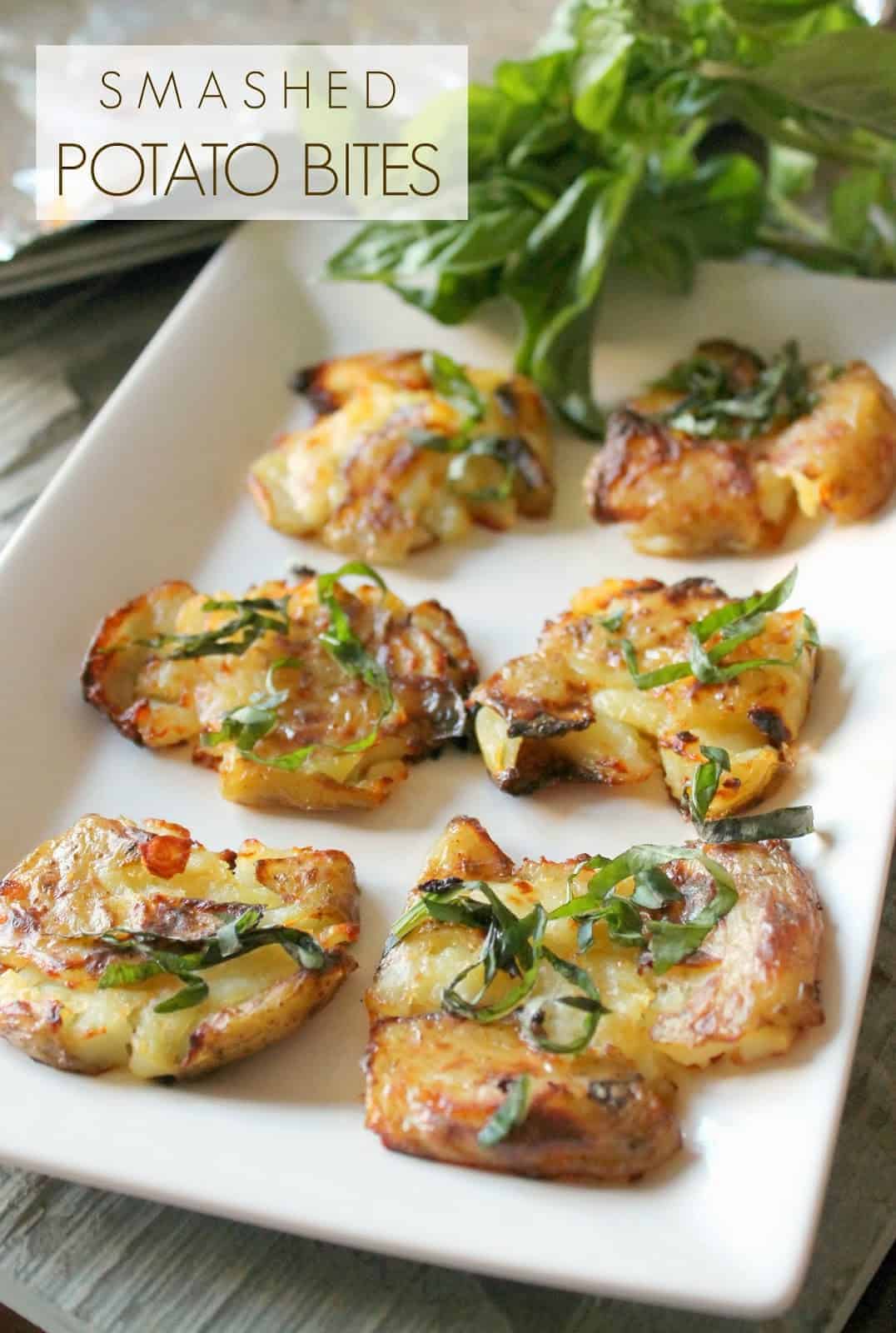 Smashed Fingerling Potatoes on a white platter topped with chopped basil.