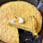 A wedge of zucchini cornbread topped with a pat of butter.