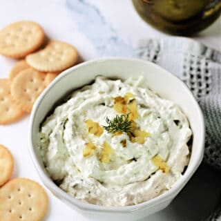 Dill Pickle Dip in a white bowl with crackers around it.
