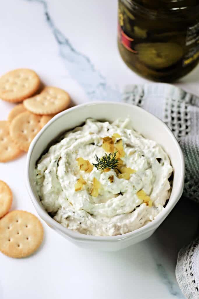 Dill Pickle Dip in a white bowl with crackers around it.