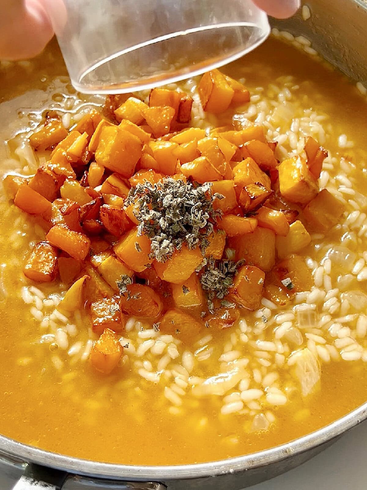 Adding roasted butternut squash and sage to arborio rice for risotto.