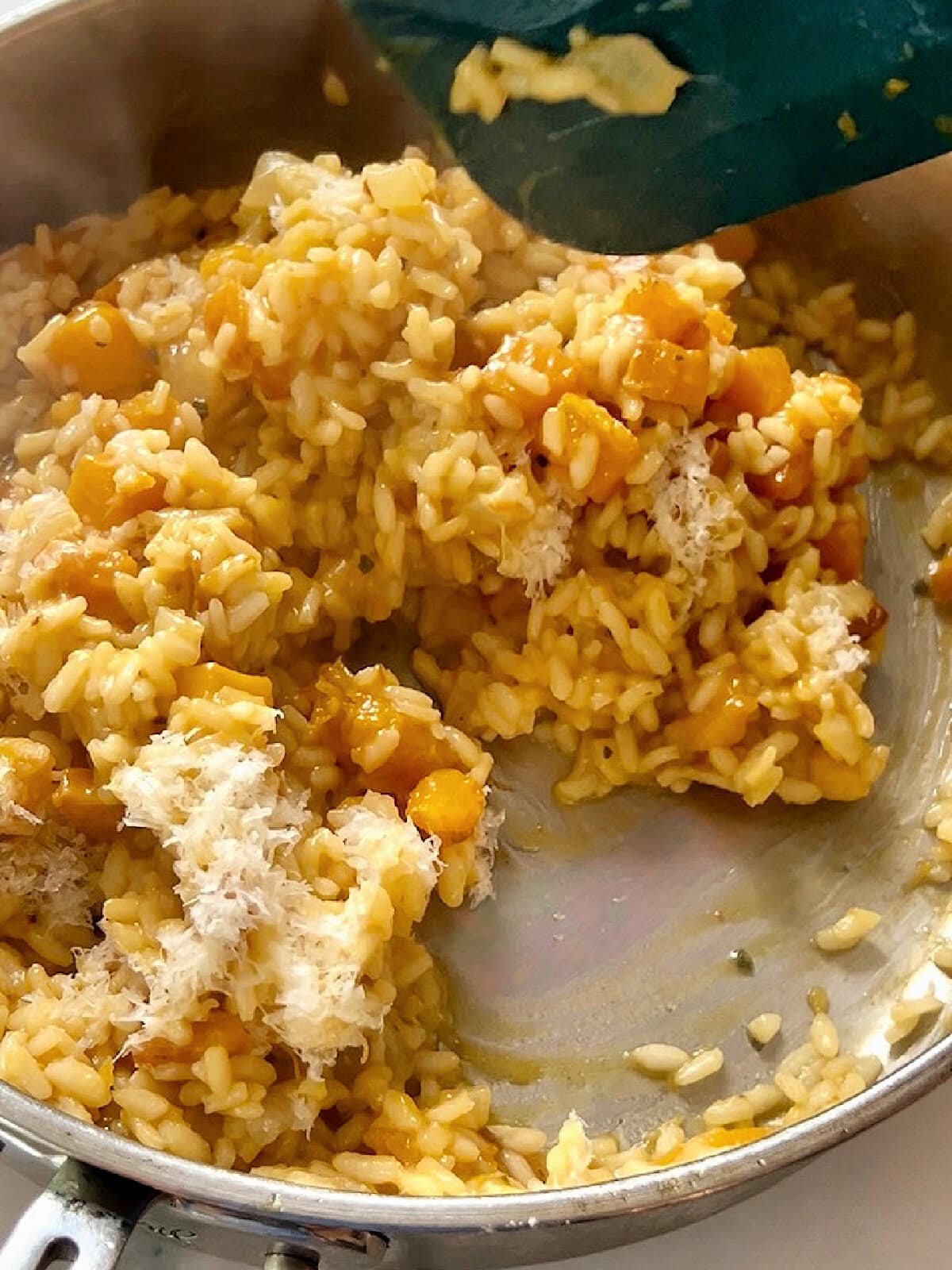 Parmesan cheese added to risotto in a pan.