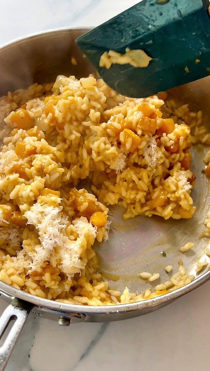 Parmesan cheese added to risotto in a pan.