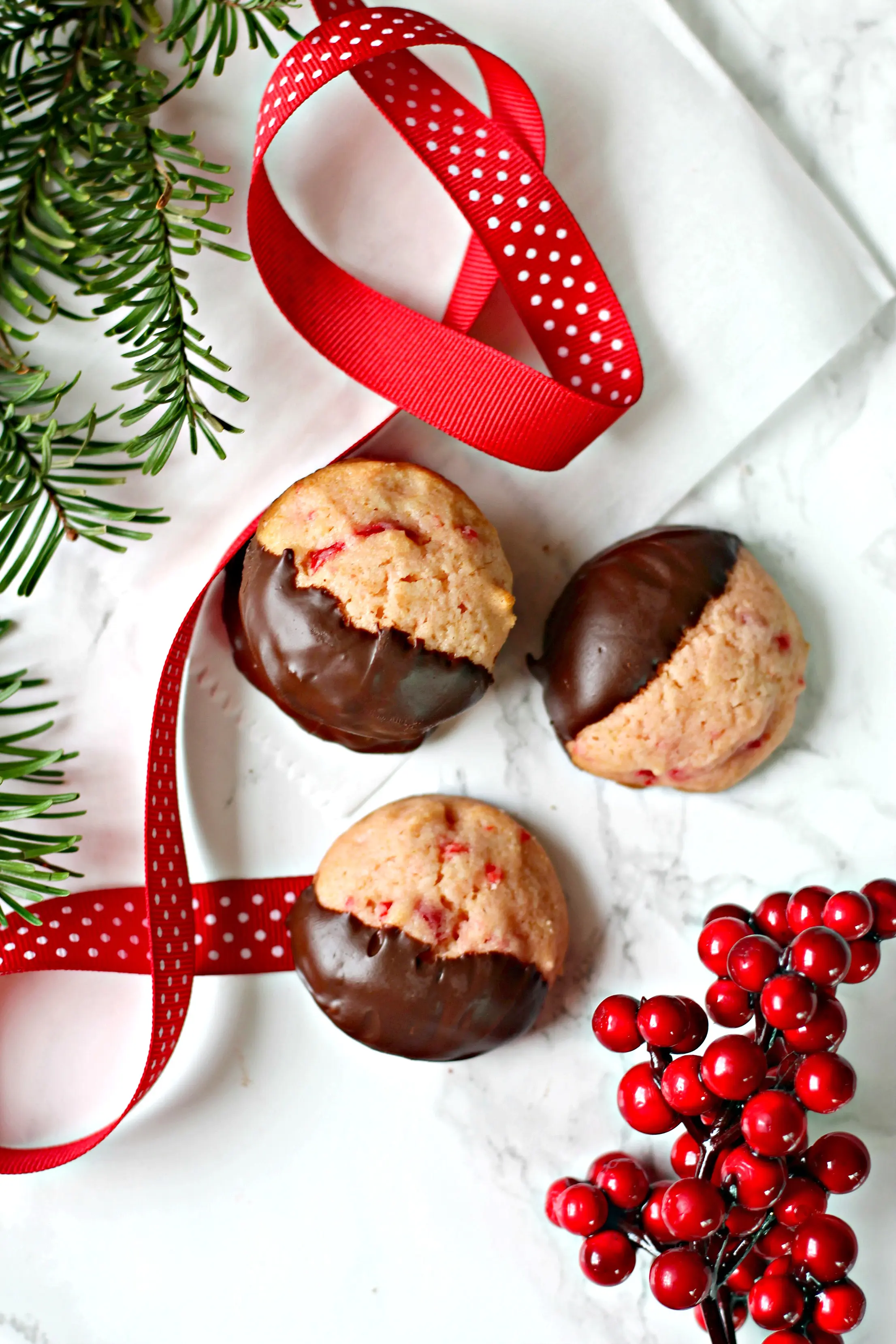 Overhead shot of Maraschino Cherry Cookies with berries, ribbon and evergreen sprig.