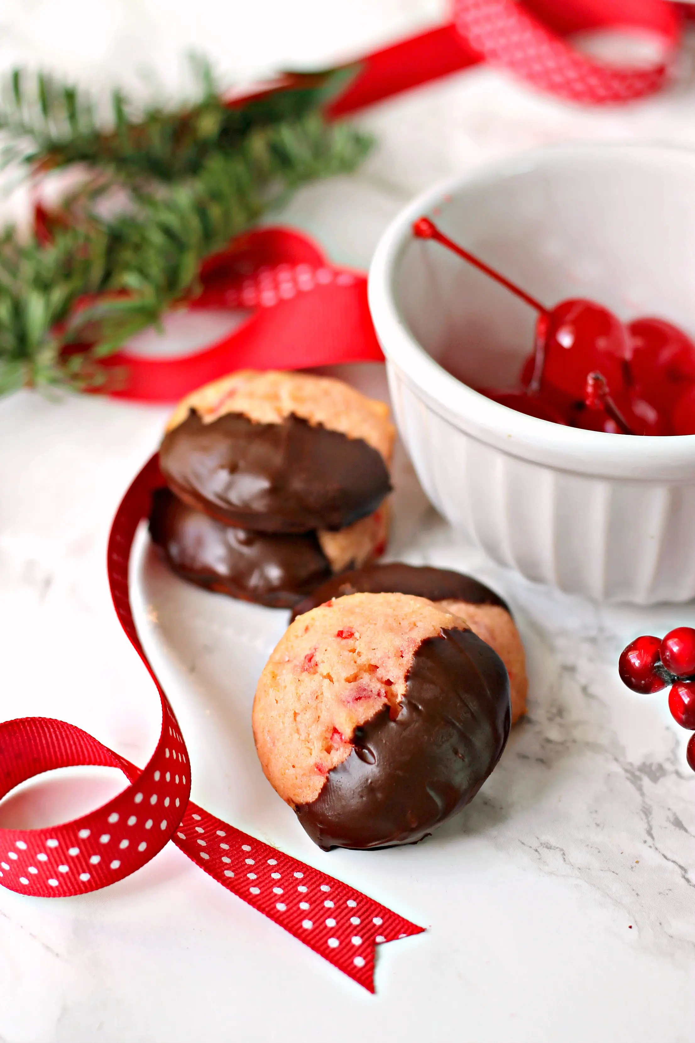 Close up of Maraschino Cherry Cookies with ribbon and evergreen.