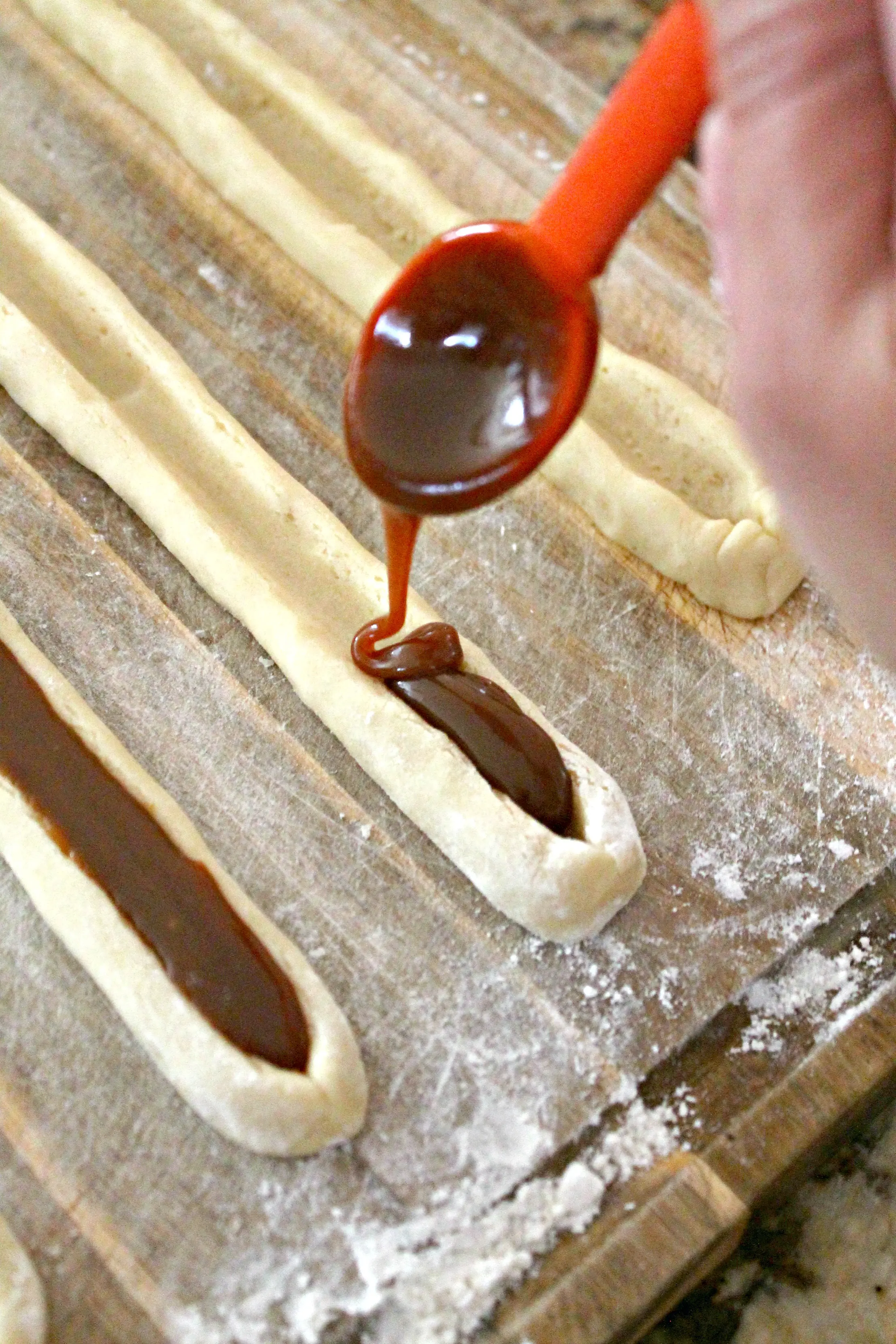 Close up of filling cookie dough logs with caramel.