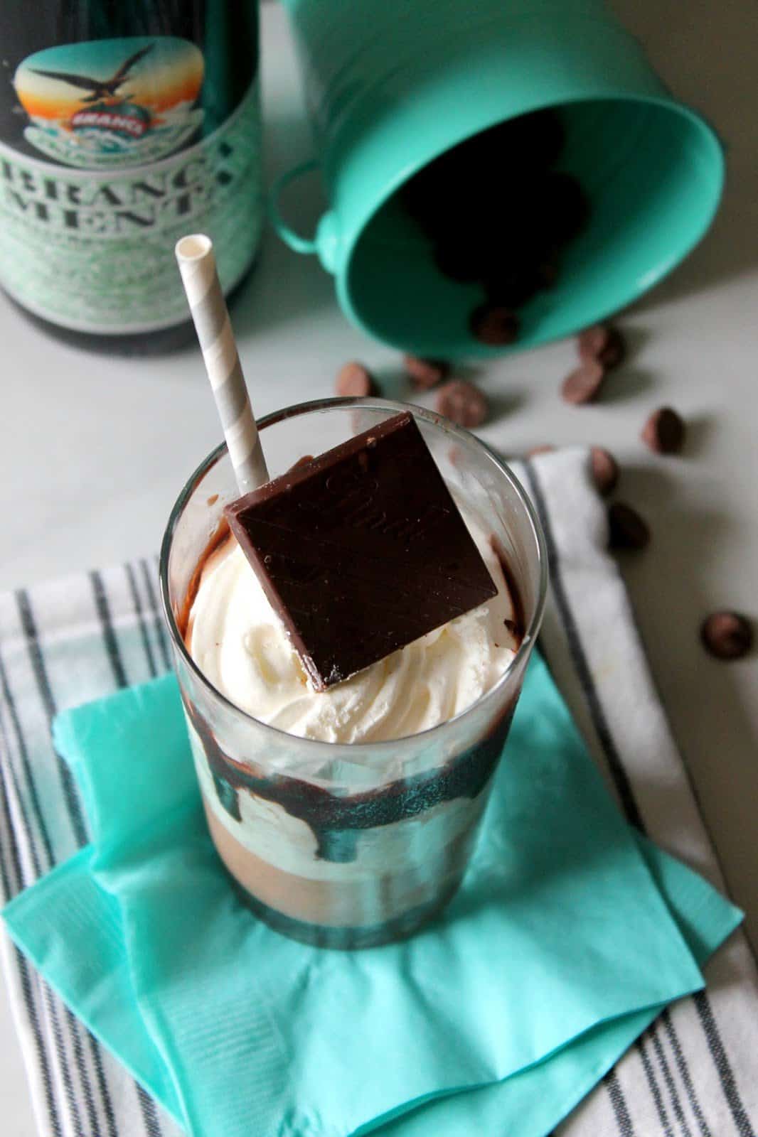 A spiked chocolate mint milkshake topped with whipped cream and a chocolate square.