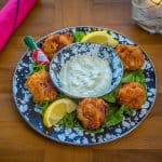 Grouper Fritters on a blue platter with dipping sauce in the center.
