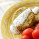 White bean burgers with yogurt sauce on a yellow plate.