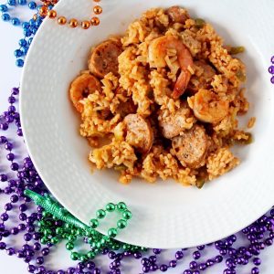 One Pot Jambalaya in a white dish surrounded by Mardi Gras Beads.