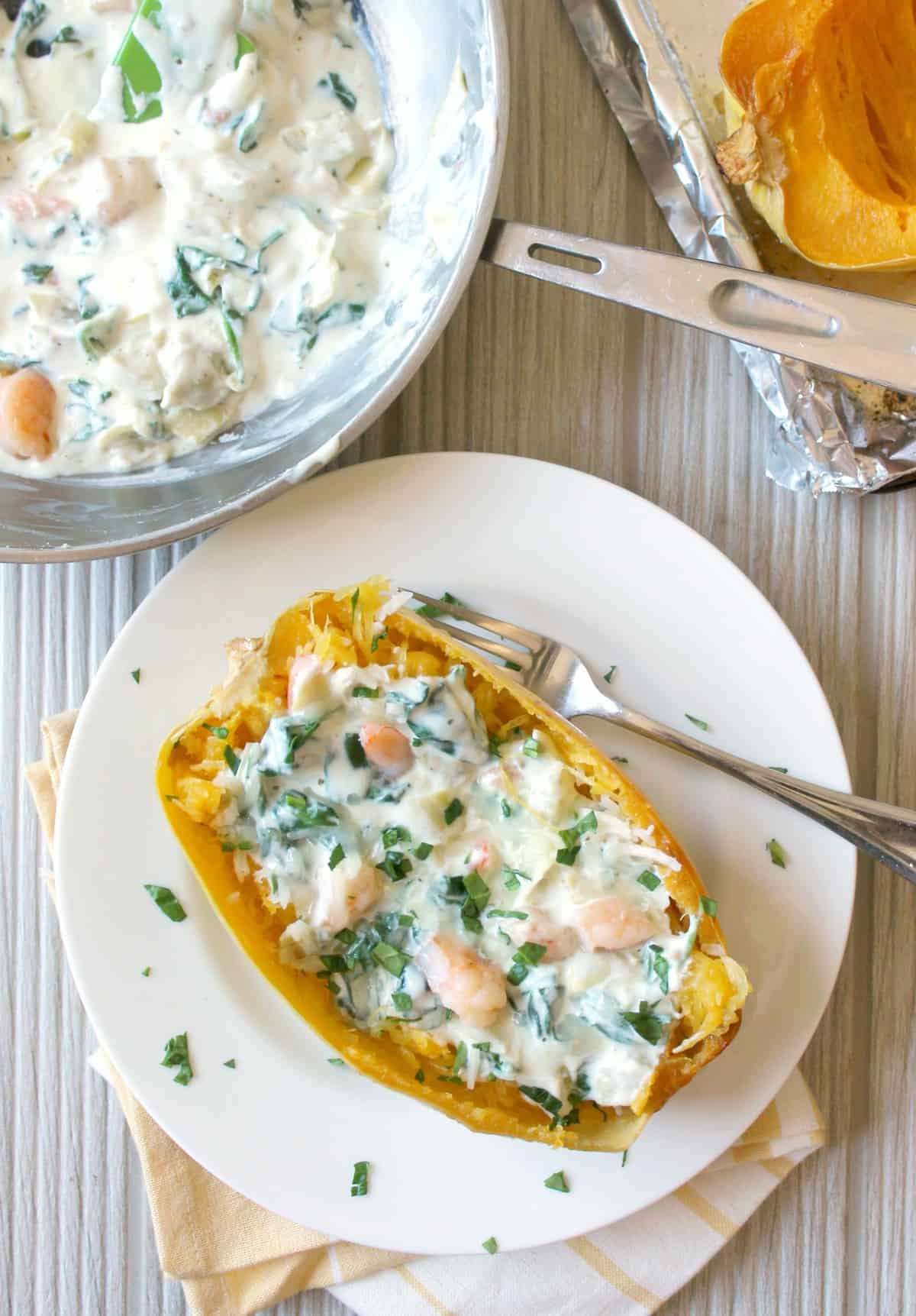 Creamy shrimp in a spinach and artichoke sauce spooned over roasted spaghetti squash boats
