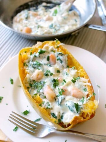 Creamy Shrimp, Spinach and Artichoke Spaghetti Squash Boats! Roasted spaghetti squash is smothered with creamy sauce reminiscent of spinach and artichoke dip, then topped with shrimp for a comforting weeknight dish!