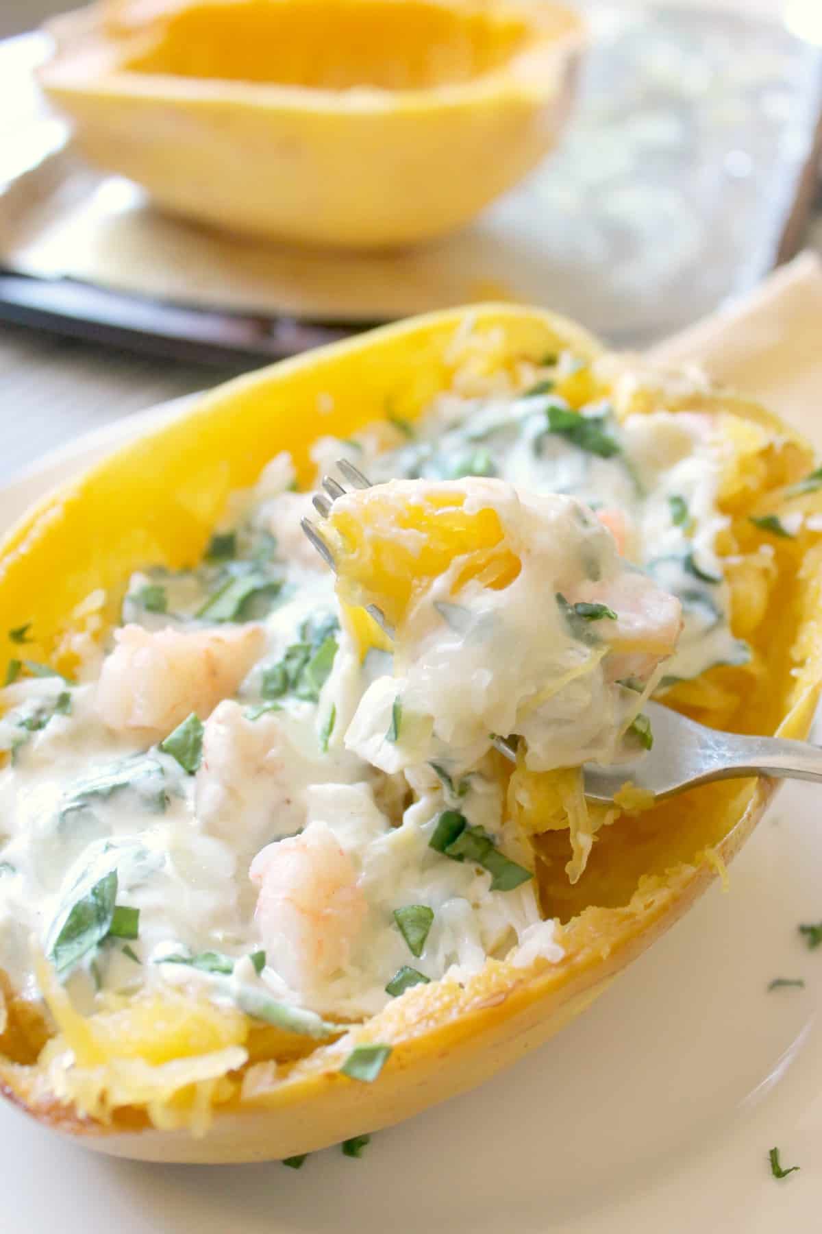 A perfect forkful of creamy shrimp in a spinach and artichoke cream sauce with roasted spaghetti squash
