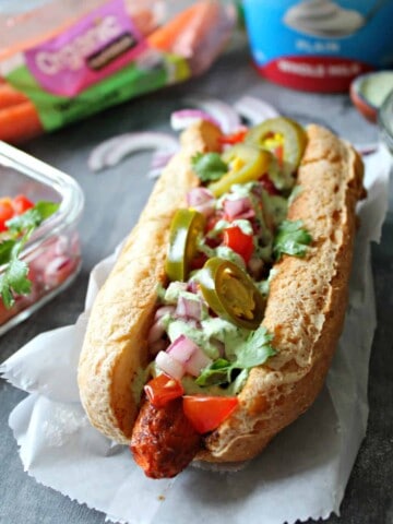 Carrot dogs on a white sheet of parchment with toppings surrounding it.
