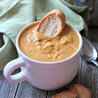 Gluten-Free Broccoli Cheddar Soup in a white mug with a piece of toasted bread dunked in.