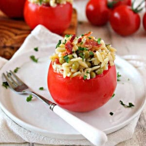 A tomato stuffed with orzo pasta salad on a white plate.