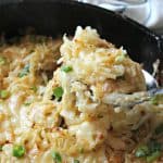 Lifting a scoop of Irish Cheddar & Cabbage Hash Browns out of a cast iron skillet.