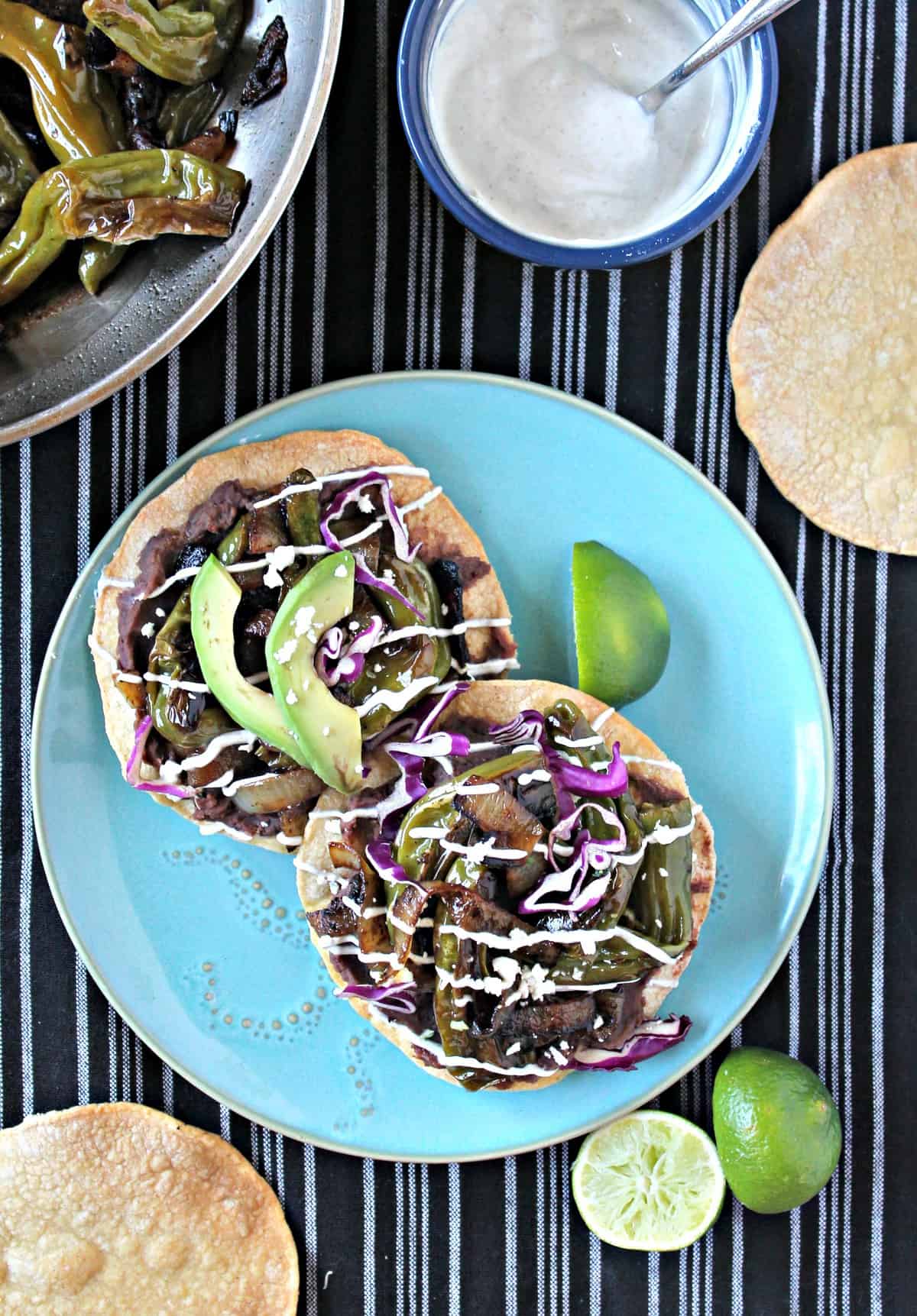 Charred Shishito Pepper & Refried Bean Tostadas! Just because these crunchy tostadas come together quickly doesn't mean they lack any flavor! Charred Shishito peppers, onions and refried beans drizzled with a Cumin & Lime Yogurt Sauce make a quick but delicious meal.