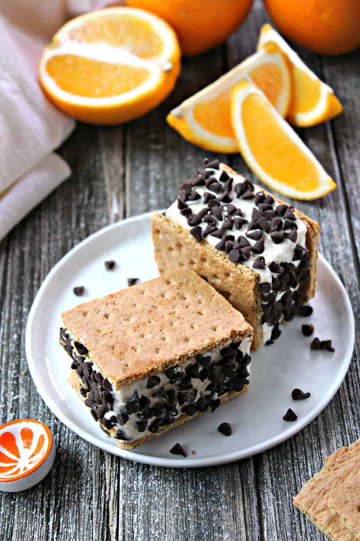 Easy No-Churn Orange-Chip Ice Cream Sandwiches! Orange-infused, no churn ice cream is cut into perfect portions, sandwiched between graham crackers & rolled in mini chocolate chips. A sweet summer dessert that's easy to whip up with your kids and even easier to eat!