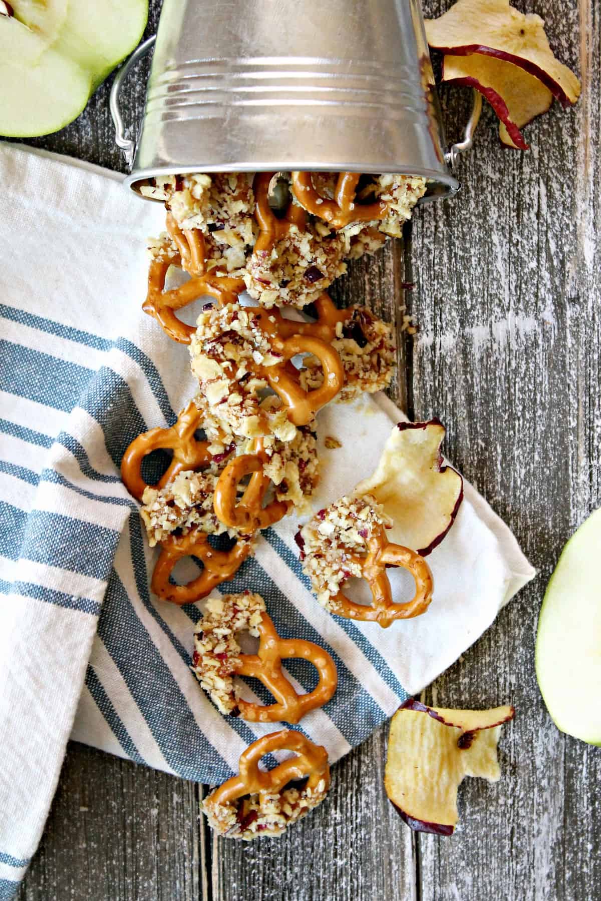 Caramel Apple Dipped Pretzel Bites! Crunchy mini pretzels dipped in sweet caramel and rolled in crushed apple chips will be the highlight of your fall dessert table! These irresistible, easy-to-make bites make fantastic game day snacks for tailgates and fall parties; they also make a great treat to package and gift for any autumn occasion.