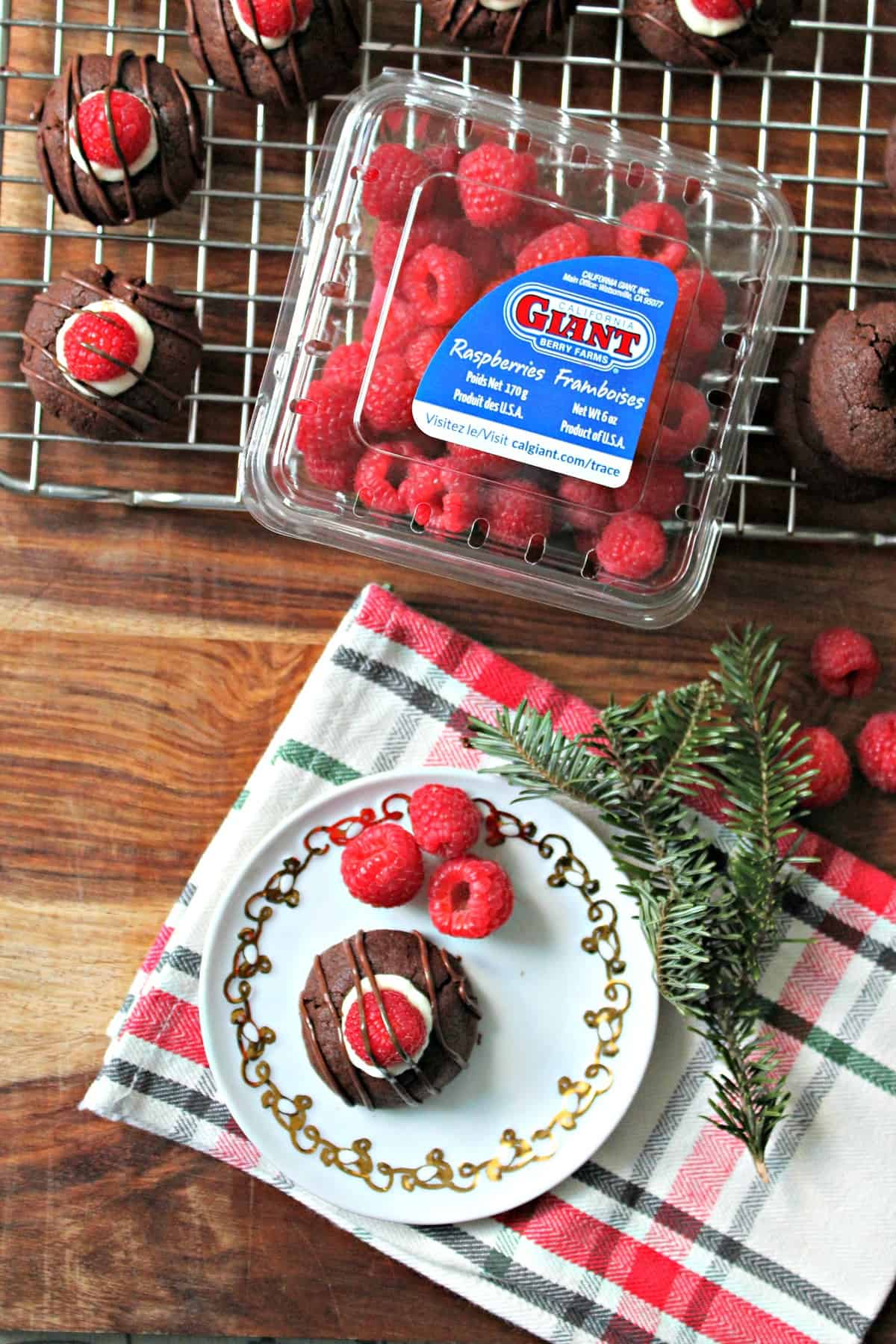 Raspberry Cheesecake Chocolate Thumbprint Cookies! This thumbprint cookie recipe will become a family favorite: Tender chocolate cookies filled with creamy "cheesecake" filling, fresh raspberries and topped with a chocolate drizzle! A beauty to share for holiday cookie exchange parties and beyond.