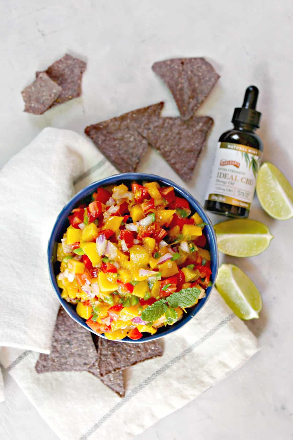 Mango Pico de Gallo  in blue bowl surrounded my blue corn tortilla chips.