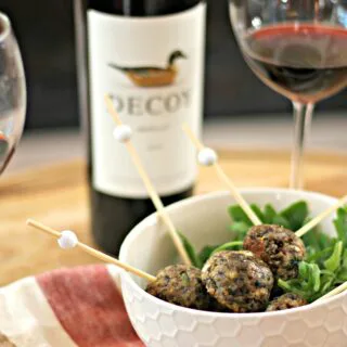 Vegetarian meatballs in a white bowl with merlot wine in the background.