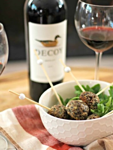 Vegetarian meatballs in a white bowl with merlot wine in the background.