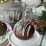 Holiday hot chocolate bomb on a small white pedestal.