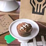 Image of a Football Pie Cookie Cup on a mini white cake plate surrounded by football party supplies.