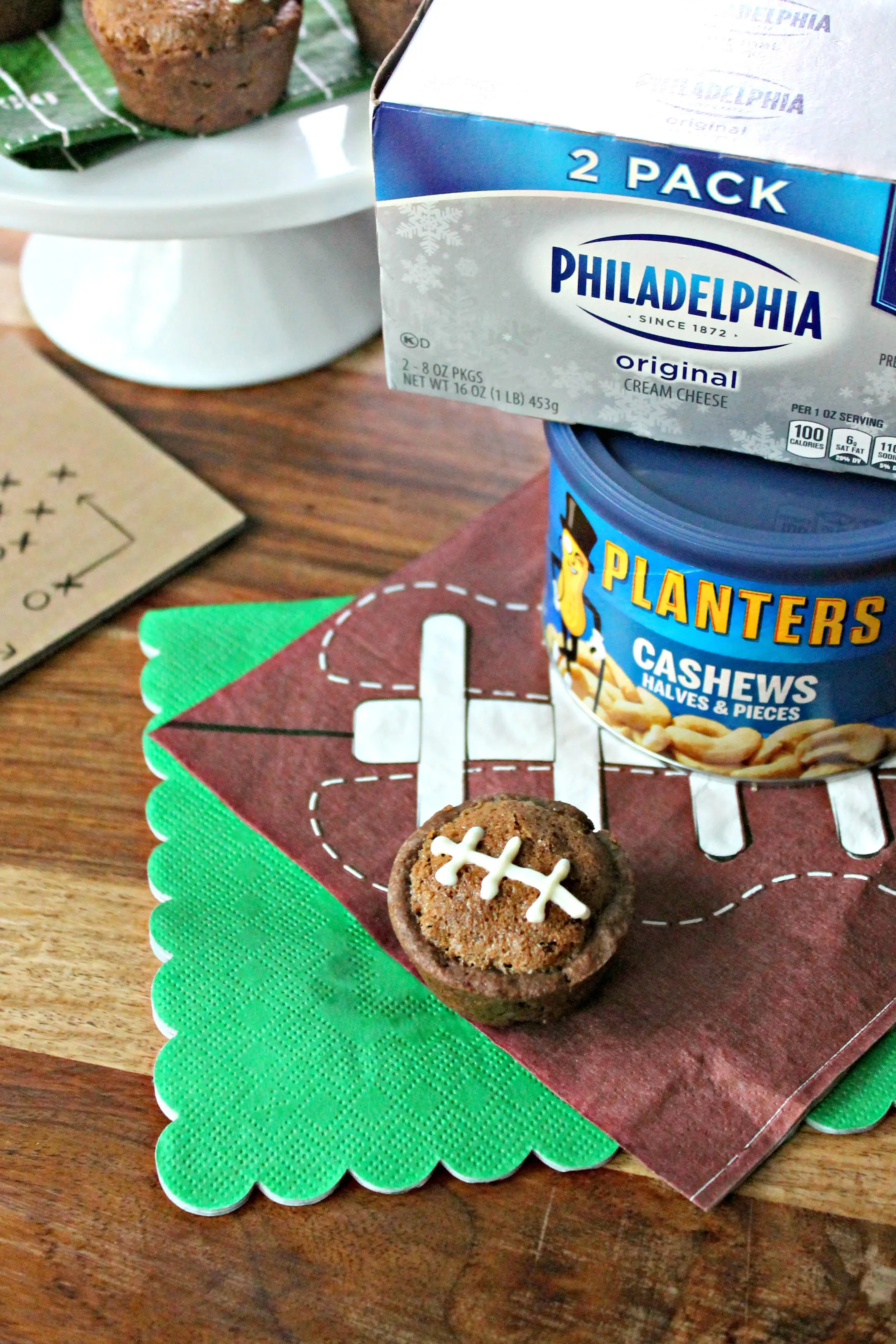 Football Pie Cookie Cup on a football napkin with can of cashews & cream cheese beside it.