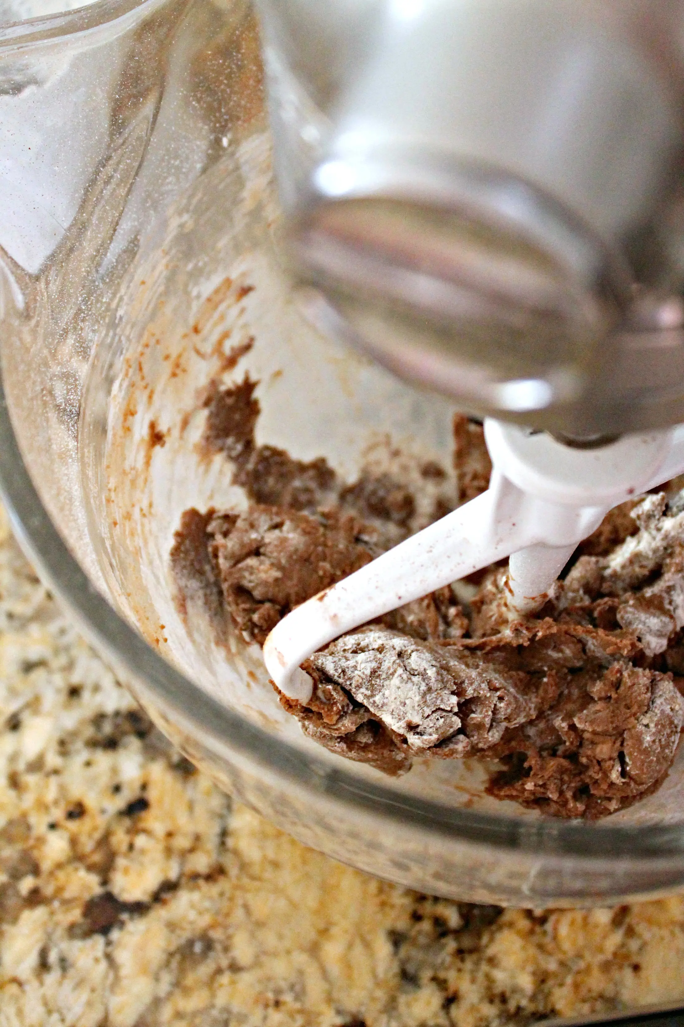 Process shot of chocolate dough for Football Pie Cookie Cups in bowl of stand mixer. 