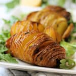 Close up shot of cooked Hasselback potato on a plate.