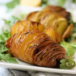 Close up shot of cooked Hasselback potato on a plate.