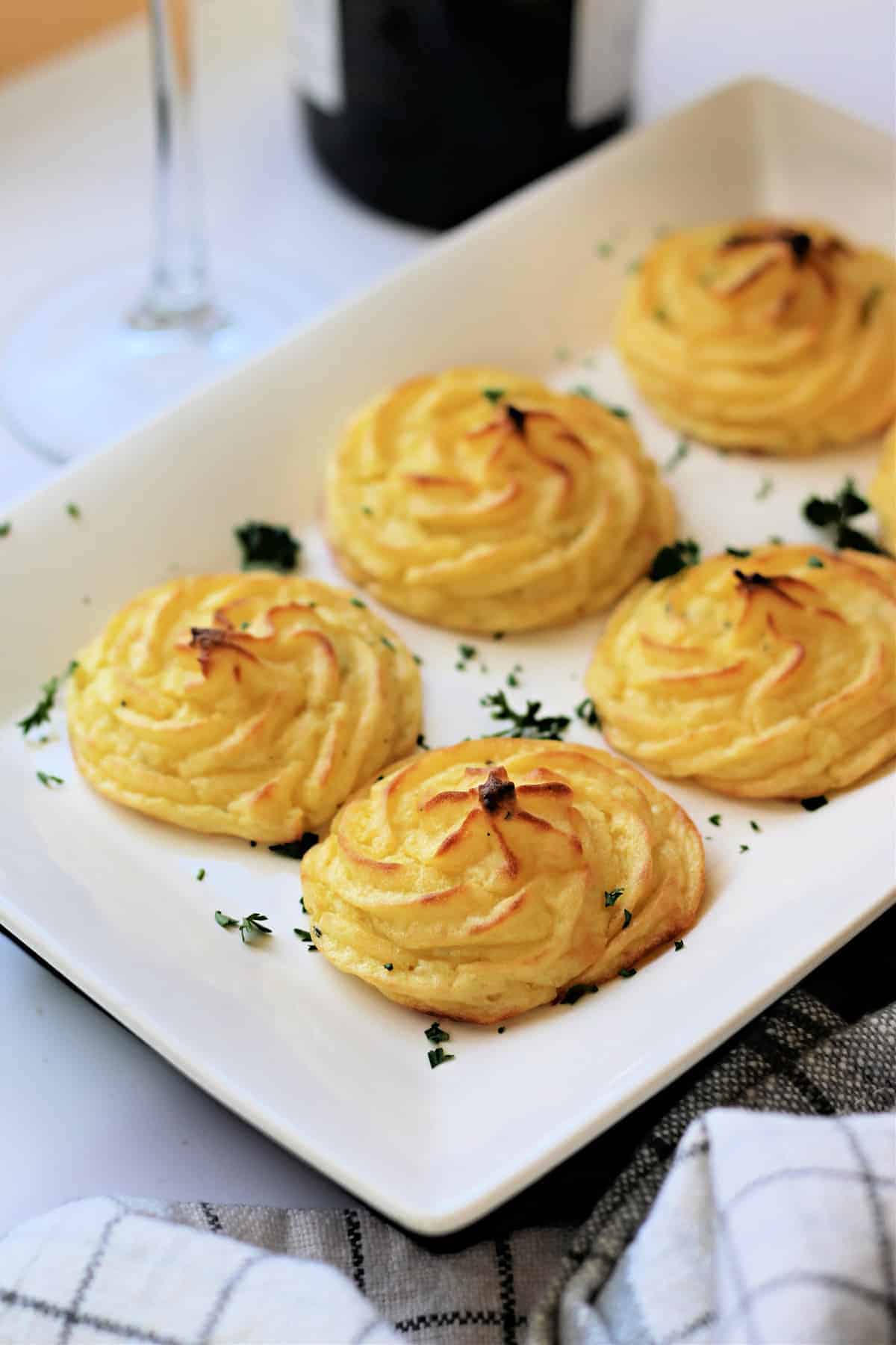 Close up of cooked Duchess Potatoes on a white serving dish.