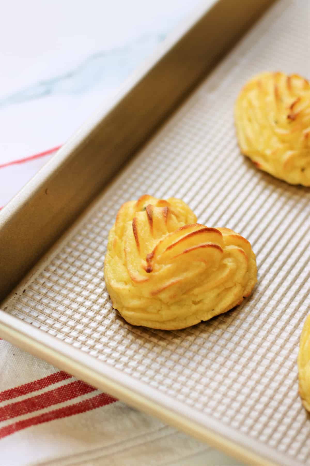 Close up of heart shaped Duchess Potatoes on a baking pan.