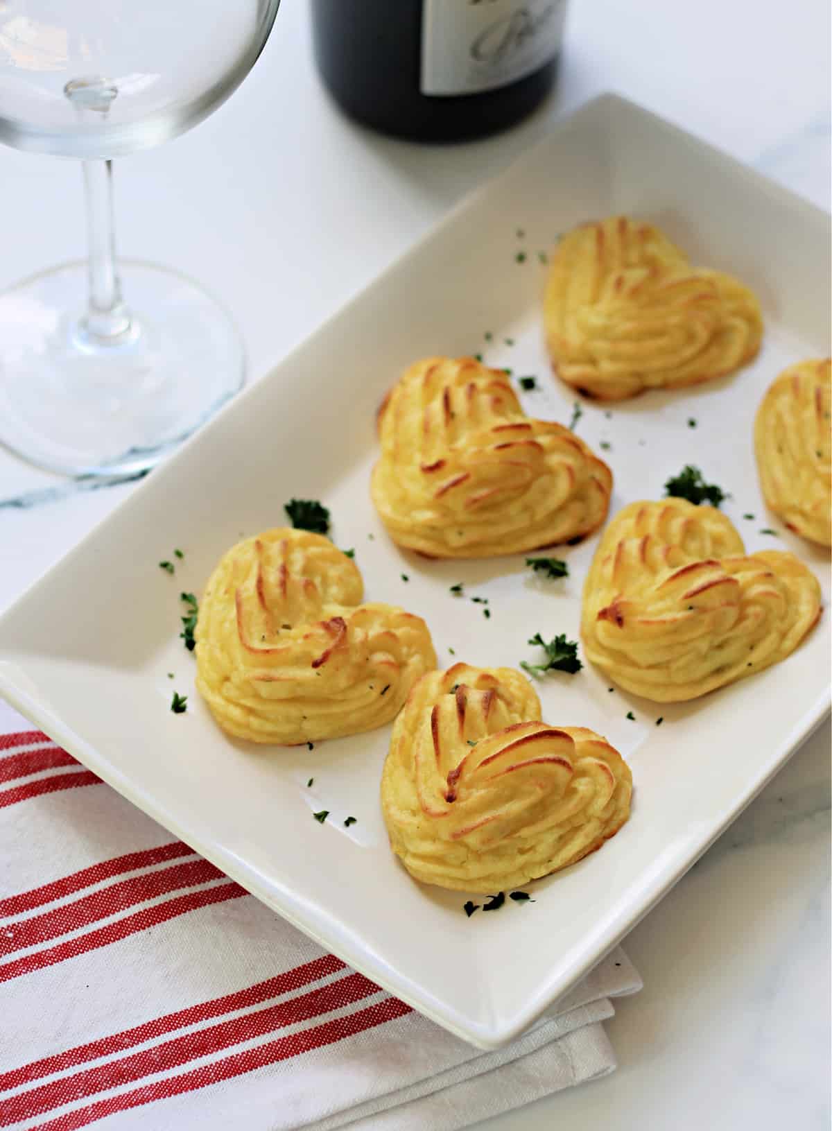 Heart-shaped Duchess Potatoes on a white serving dish.