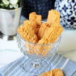 Southern Cheese Straws in a clear glass dish with decorative elements surrounding.