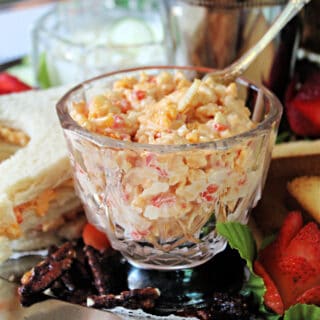 Pimento Cheese in a glass serving dish with a silver spreader.