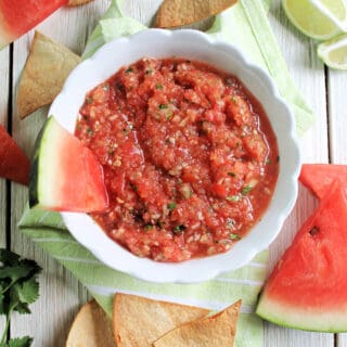 Grilled Watermelon Salsa in a white bowl surrounded by watermelon slices and tortilla chips.
