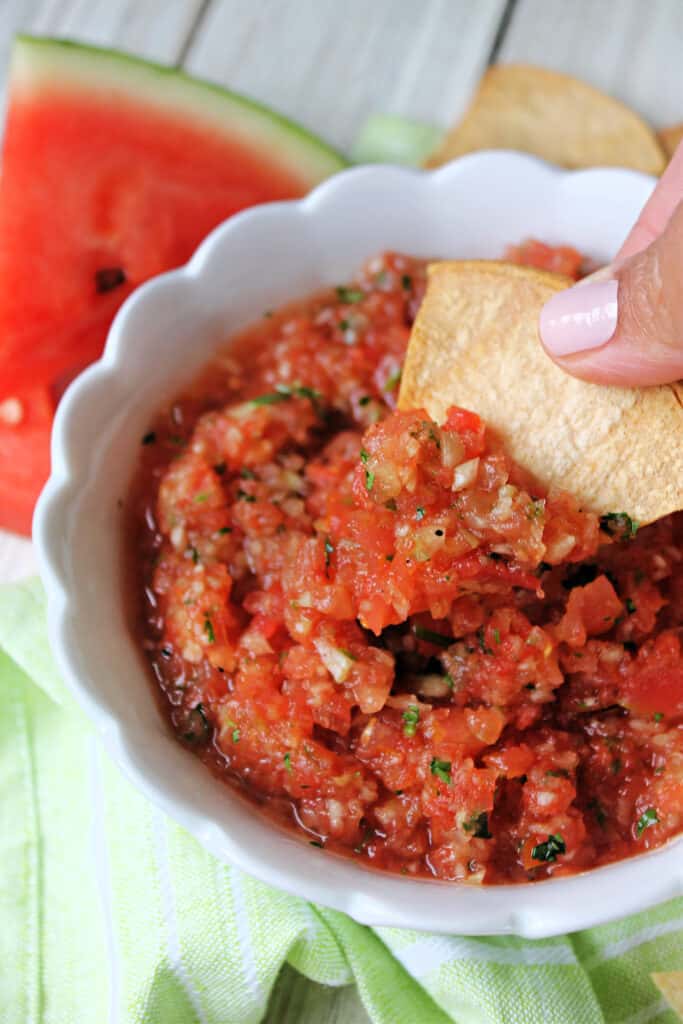 Hand dipping a tortilla chip into Grilled Watermelon Salsa